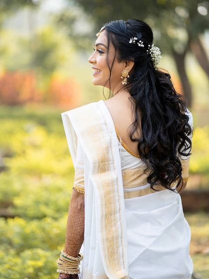 A side profile of the Christian bride, showcasing her beautiful open hairstyle with soft curls and delicate floral accessories.