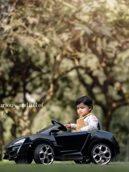 Cute, curious and full of cheer. A toddler takes a thoughtful pause from driving his toy car.