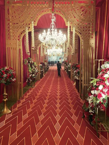 For those who dream of timeless grandeur, I craft entrances that speak the language of royalty. This opulent passageway for a royal Indian wedding features intricate gold-lacquered arches, magnificent chandeliers, and a rich red carpet, setting a majestic tone from the very first moment.