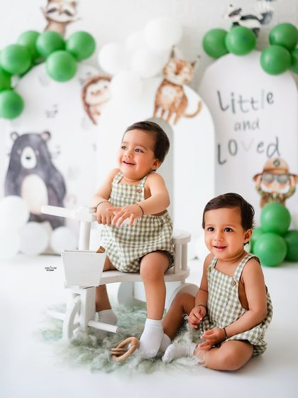 One twin rides the tricycle while the other looks on in this adorable twin birthday shoot.