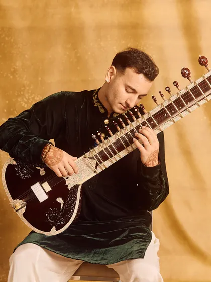 A close-up of my hands on the sitar, wearing a green velvet kurta. The rich texture of the fabric adds a luxurious feel.