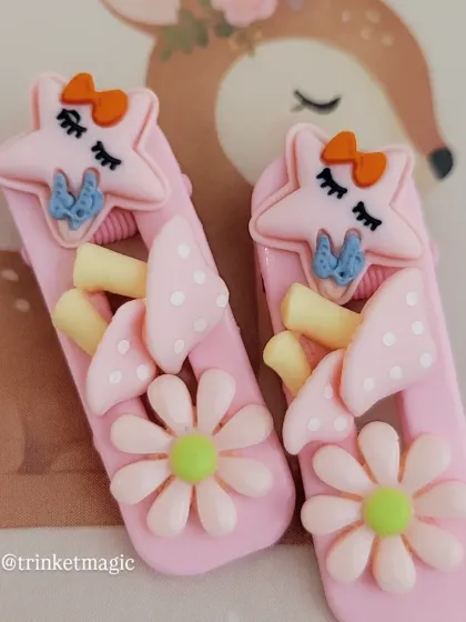 This pair of pink hair clips has a whimsical, forest-y vibe, with a sleepy star, mushrooms, and a daisy.