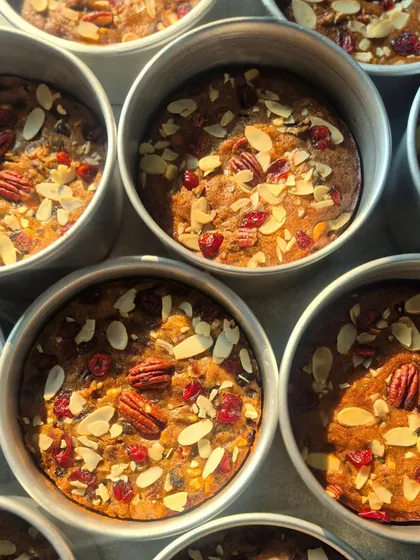 A batch of my Christmas plum cakes, fresh out of the oven. The sunlight catches the glistening cranberries and nuts on top.