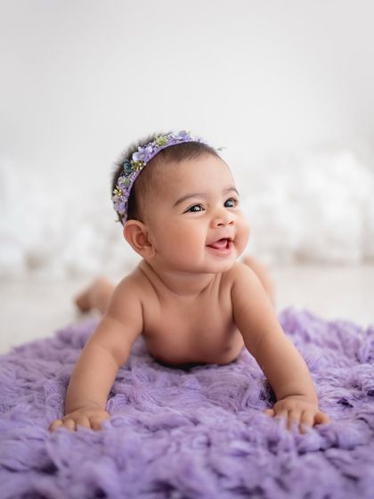 A sweet baby girl during her tummy time session on a plush purple blanket.