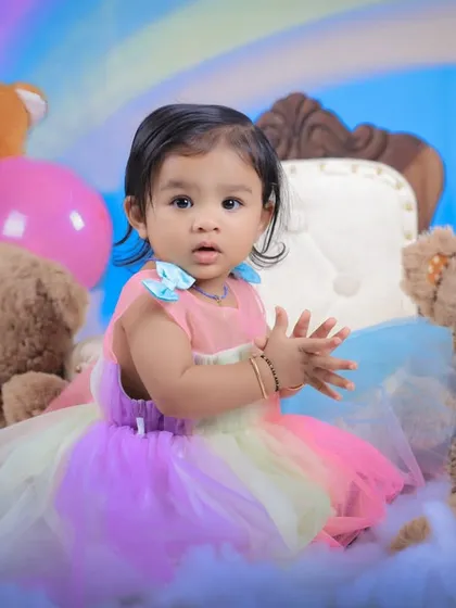 A playful, clapping moment during the rainbow-themed shoot. We create a fun atmosphere to bring out these adorable, natural reactions from children.