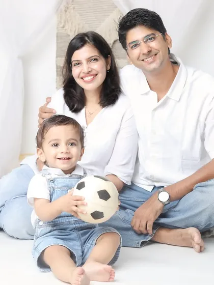 A bright and happy family photo with everyone smiling at the camera. The little one is holding a soccer ball, showing his budding interests.