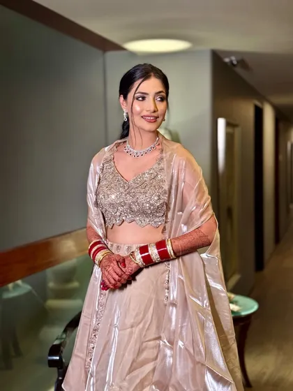 A candid shot of this beautiful reception look. The bride wears a shimmering champagne lehenga with a simple diamond necklace, paired with a fresh, glowing makeup look.