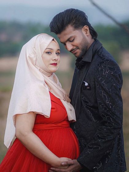 I believe every mom deserves to feel beautiful while honoring her style. This client looks radiant in a vibrant red gown paired with her hijab, and her partner's stylish black blazer completes their elegant outdoor maternity shoot.