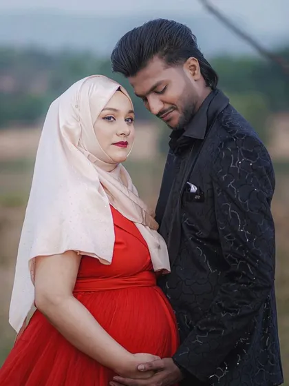 I believe every mom deserves to feel beautiful while honoring her style. This client looks radiant in a vibrant red gown paired with her hijab, and her partner's stylish black blazer completes their elegant outdoor maternity shoot.