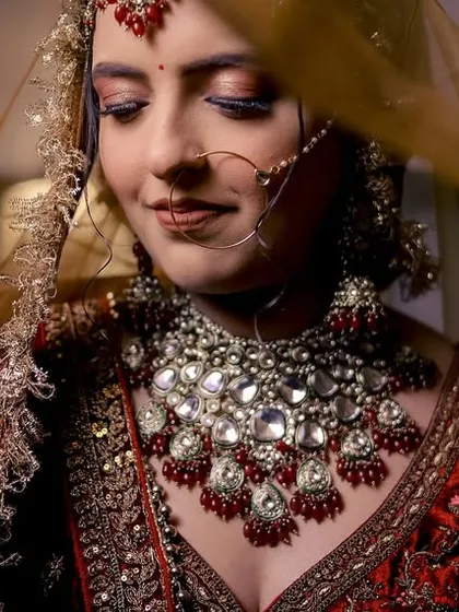 A beautiful close-up of a bride, her face gently veiled, highlighting her intricate jewelry and serene expression.