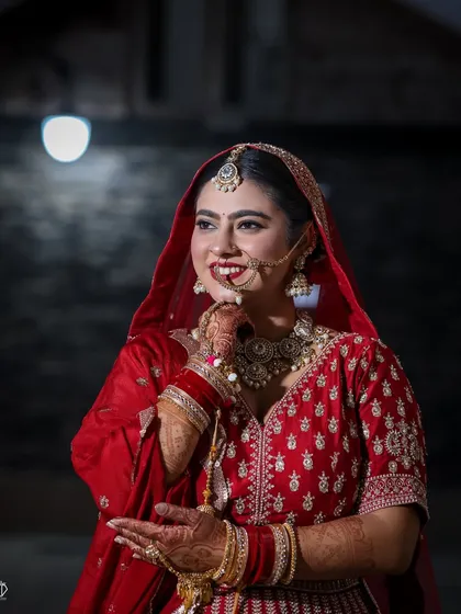 A beautiful three-quarter portrait of the bride, capturing her happy expression and the intricate details of her nath and jewelry under soft lighting.