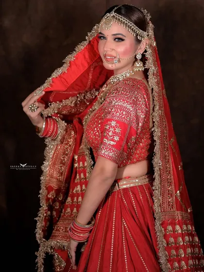 A side-view portrait of the bride looking over her shoulder, showing the back of the blouse and her smile.