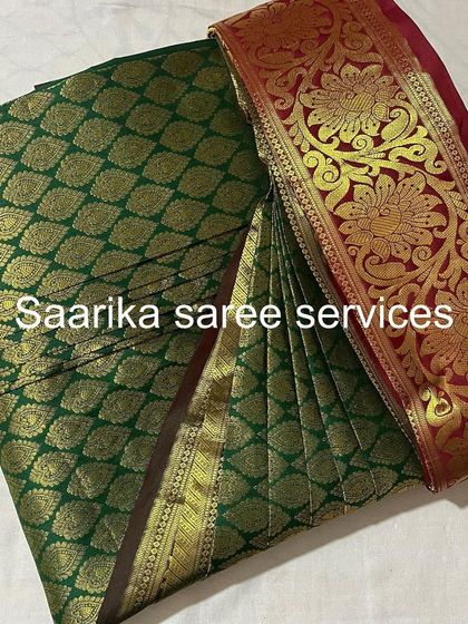 A rich green and red Kanjivaram saree, pleated and ready for a wedding. This service is a must for bridal trousseaus.