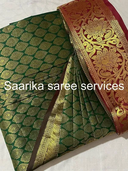 A classic dark green and red bridal saree, folded to protect its heavy work.
