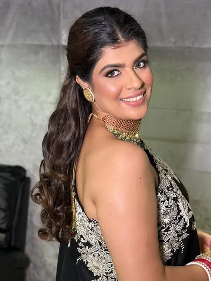 A chic and modern look for a wedding guest, featuring a half-up ponytail and soft waves.