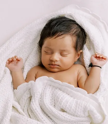 The classic newborn portrait. This peaceful, sleeping baby, swaddled snugly in a soft white blanket, shows the serene beauty of those very first days.