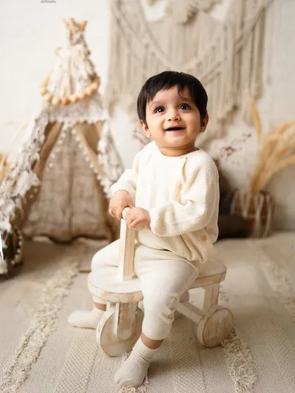 That happy, curious smile is what milestone sessions are for. I designed this neutral-toned boho setup to let this little one's bright personality shine through as he explores his world.