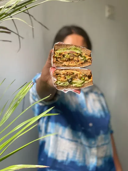 A closer look at the delicious cross-section of our Vietnamese BBQ Chicken Sandwich. You can see the tender chicken, fresh veggies, and our special sauces all packed into hearty multigrain bread.