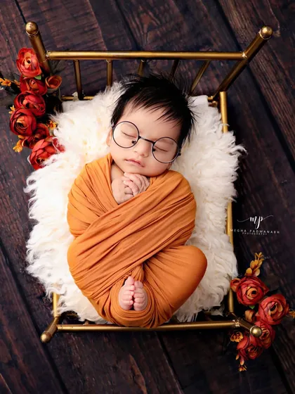 For the parents who love a touch of whimsy, we offer creative setups like this adorable 'little scholar' theme. Complete with tiny glasses, this baby is resting on a miniature golden bed, making for a truly unique portrait.