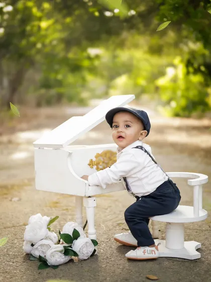 A tiny musician at his white piano. We have a variety of props like this miniature piano to add a touch of charm and creativity to your child's first birthday photos in our garden.