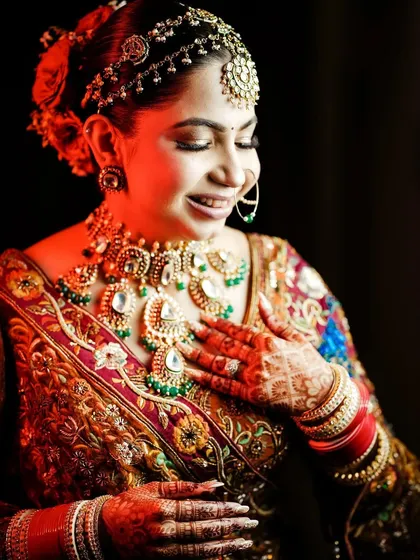 A radiant bridal portrait with dramatic red lighting, highlighting her intricate jewelry.