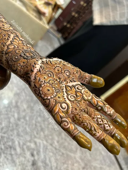 A full view of Zoya's hand and forearm, showcasing the complete engagement henna design.