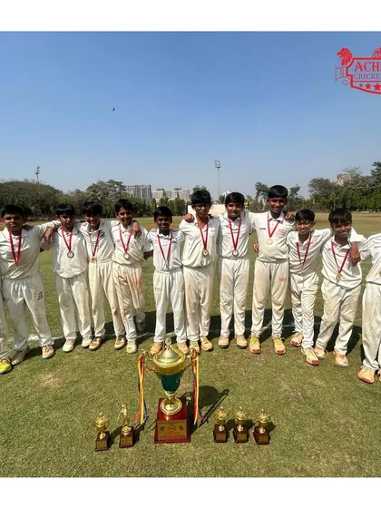 The full squad of U-12 champions posing with their medals and the ASMC tournament trophy.