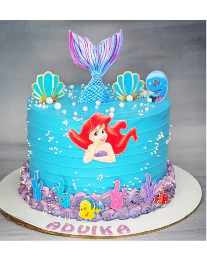 An underwater mermaid cake with a basic vanilla flavor. This design features Ariel, a shimmering mermaid tail, and colorful coral details for a 9th birthday.