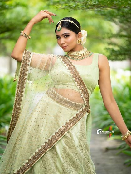 A full-body shot of a model in a light green lehenga, showcasing the outfit's flow and elegance with a dynamic pose.