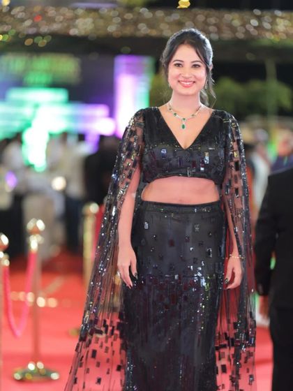 A full-length shot of Anusha Rai's stunning black ensemble with a sheer, sequined cape.