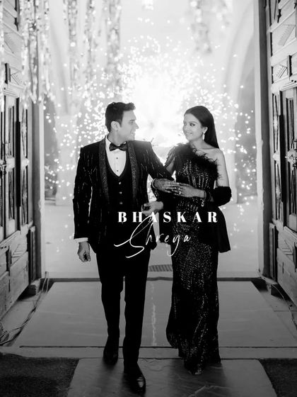 A classic, elegant entrance. This black and white shot captures the couple's sophisticated style as they walk into their cocktail party, framed by sparklers.