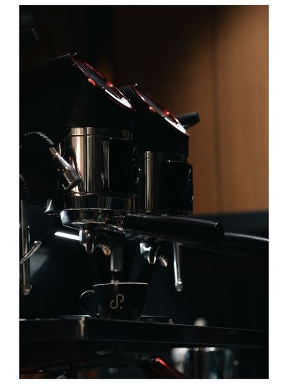 A close-up of an espresso machine in action, pouring a shot into a branded cup. This image highlights the craft and machinery behind a perfect cup of coffee.