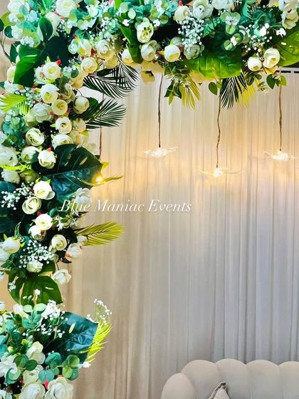 A close-up of the floral arch, showcasing the mix of white roses, baby's breath, and various green leaves like monstera and palm. This highlights the detail and variety in my floral work.