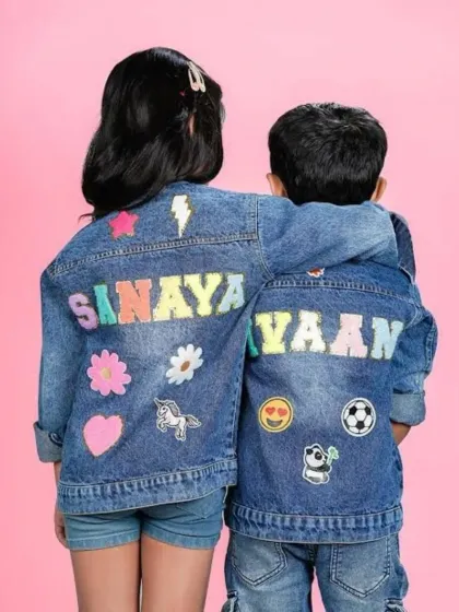 My custom denim jackets are perfect for the little ones. This photo shows a matching set for a brother and sister, each personalized with their names and a selection of six fun patches like unicorns, flowers, soccer balls, and emojis.