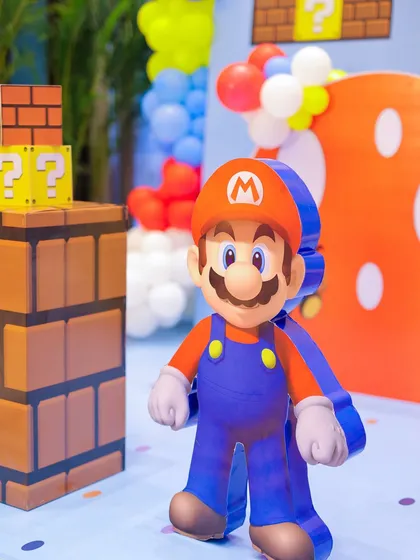 A life-sized Mario cutout stands proudly in front of a backdrop of question blocks and a giant mushroom. The attention to character detail makes the theme feel authentic and exciting.