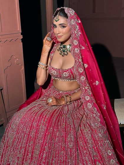 A full-length view of this modern bride in her stunning red lehenga. Her makeup is designed to be soft yet striking, with glowing skin that radiates elegance and grace from head to toe.