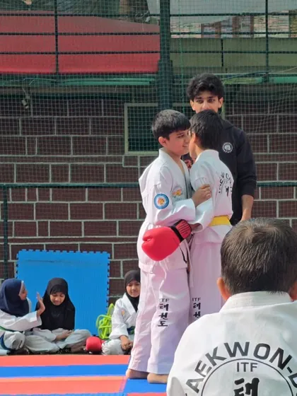 I am refereeing a friendly sparring match between two young students, teaching them control and respect.
