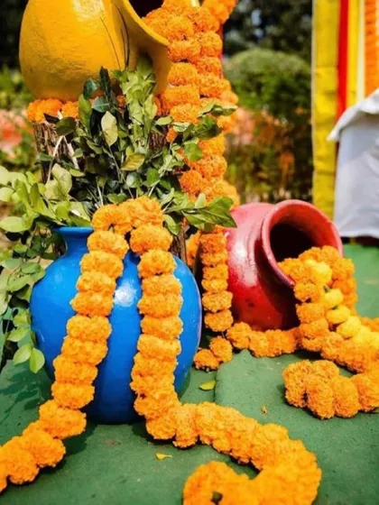 Here I have used colorful matkas of different sizes as decorative props. Garlands of orange marigolds are arranged to look like they are spilling out of the pots onto the ground.