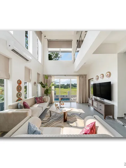 This view of the living room at Casa D Umravi looks out onto the pool and verdant fields beyond. The high ceilings and large glass doors blur the line between indoors and out, creating a perfect holiday atmosphere.