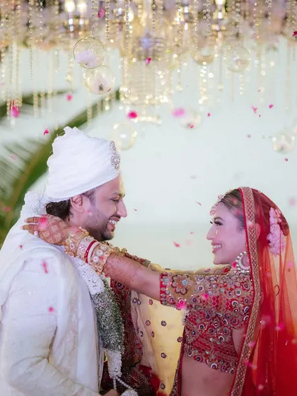 A moment of pure joy and fun during the varmala exchange. The bride's laughter is infectious as they celebrate their union under a shower of petals.