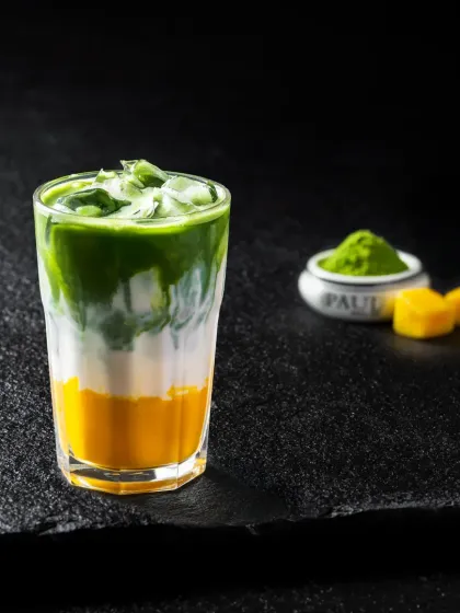 A layered iced matcha drink with a mango base, creating a beautiful gradient of yellow, white, and green.