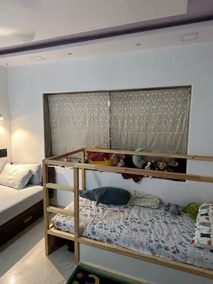 This children's bedroom features a wooden bunk bed alongside a custom single bed with built-in drawers. This setup is ideal for saving space while providing ample sleeping and storage options.