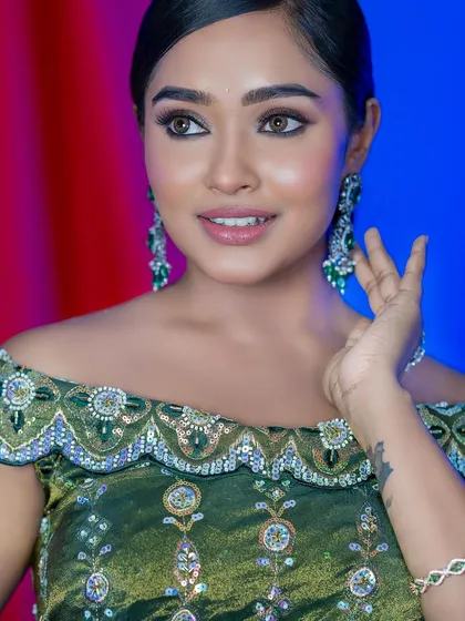 A happy, smiling portrait of the model in the green blouse, showing how makeup can bring out a person's joy.