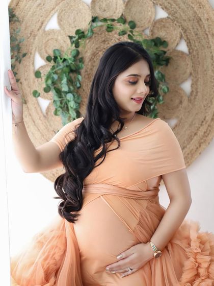 A portrait of a glowing mommy-to-be. Her happy expression and the gentle way she holds her bump in this peach gown say it all.