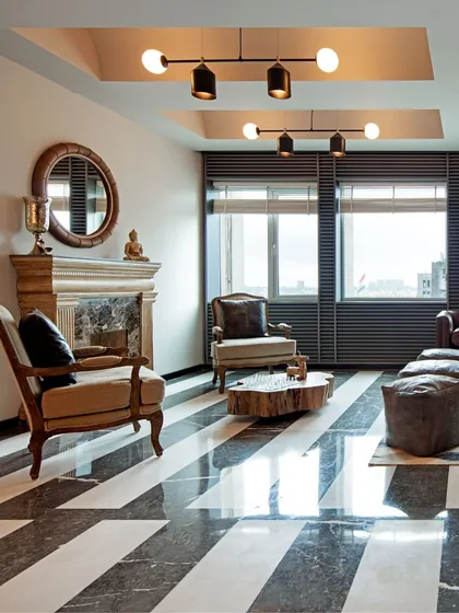 A lounge with bold black-and-white striped marble flooring. This graphic element makes a strong statement, complemented by classic furniture and a traditional fireplace mantel for an eclectic mix.