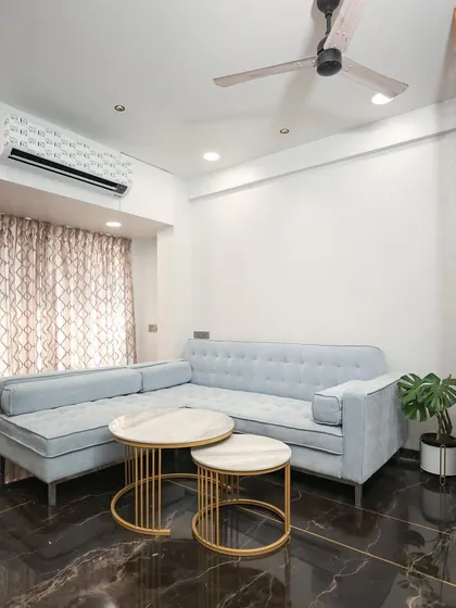 A custom powder-blue L-shaped sofa provides ample seating, while the nested coffee tables add flexibility and a modern touch.