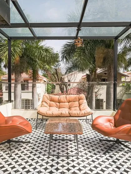 I design outdoor spaces to be quiet escapes from the everyday. This terrace, tucked among palm trees, is a soft retreat. The combination of modern leather seating, bold geometric floor tiles, and a glass roof creates a stylish sanctuary where you can unwind.