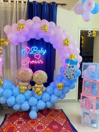 A "twin-themed" baby shower ring with two baby foil balloons, "BABY" blocks, and a pink and blue color scheme.