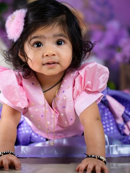 A playful crawling pose from a toddler in a traditional dress, capturing her energy and movement.