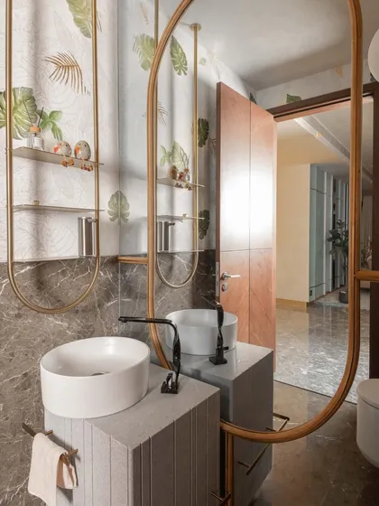 In this powder room, we combined natural stone with delicate metalwork to create a space that feels like a sanctuary. The custom vanity features fluted stone drawers, while the oversized mirror and nature-inspired wallpaper expand the room and bring the outdoors in.